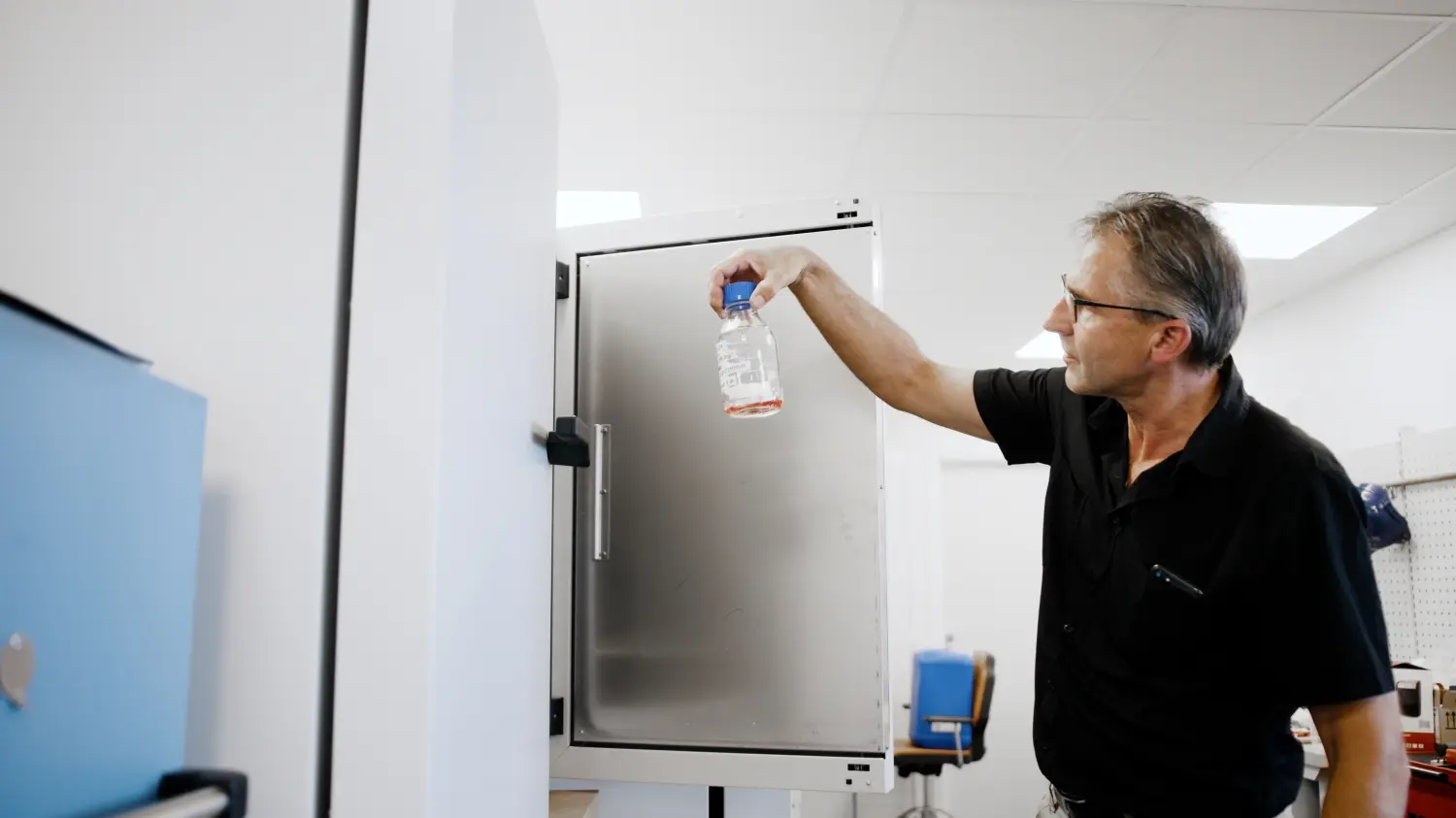 Billede af medarbejder fra en testfacilitet, som holder en prøve i et laboratorium 